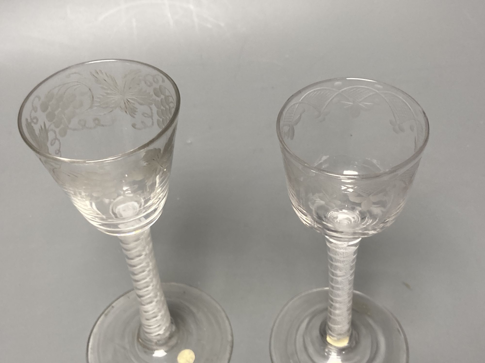 Two George III double series opaque twist stem cordial glasses, c.1760-70, with wheel engraved funnel and ogee bowls, 14.7cm and 14cm